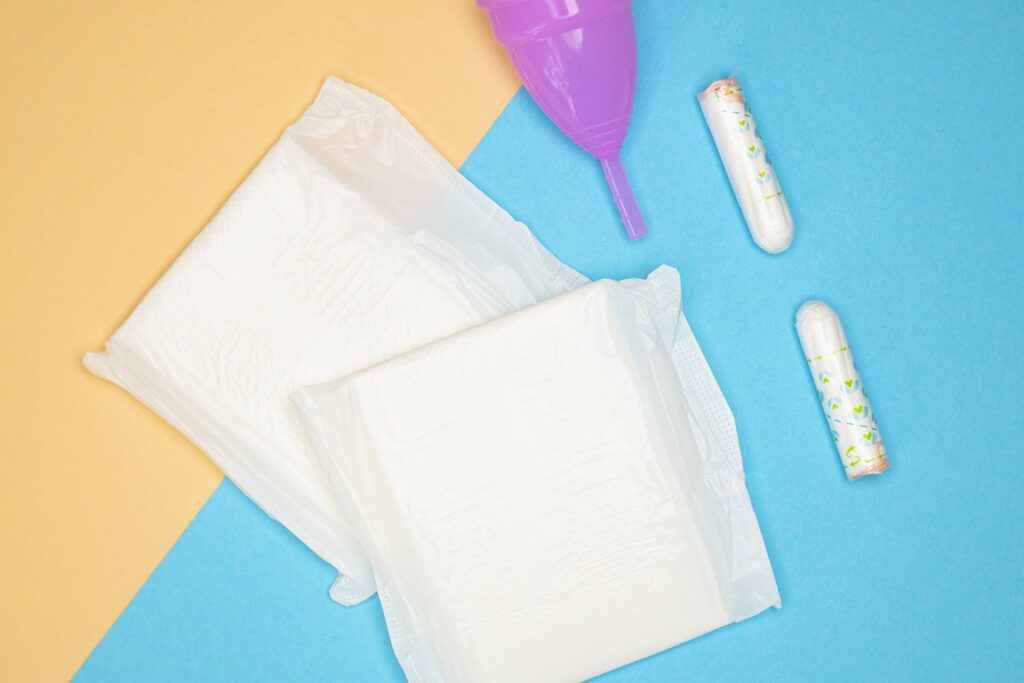 Menstrual health products and supplies (pads, tampons, menstrual cups or reusable cups) on a colorful background.
