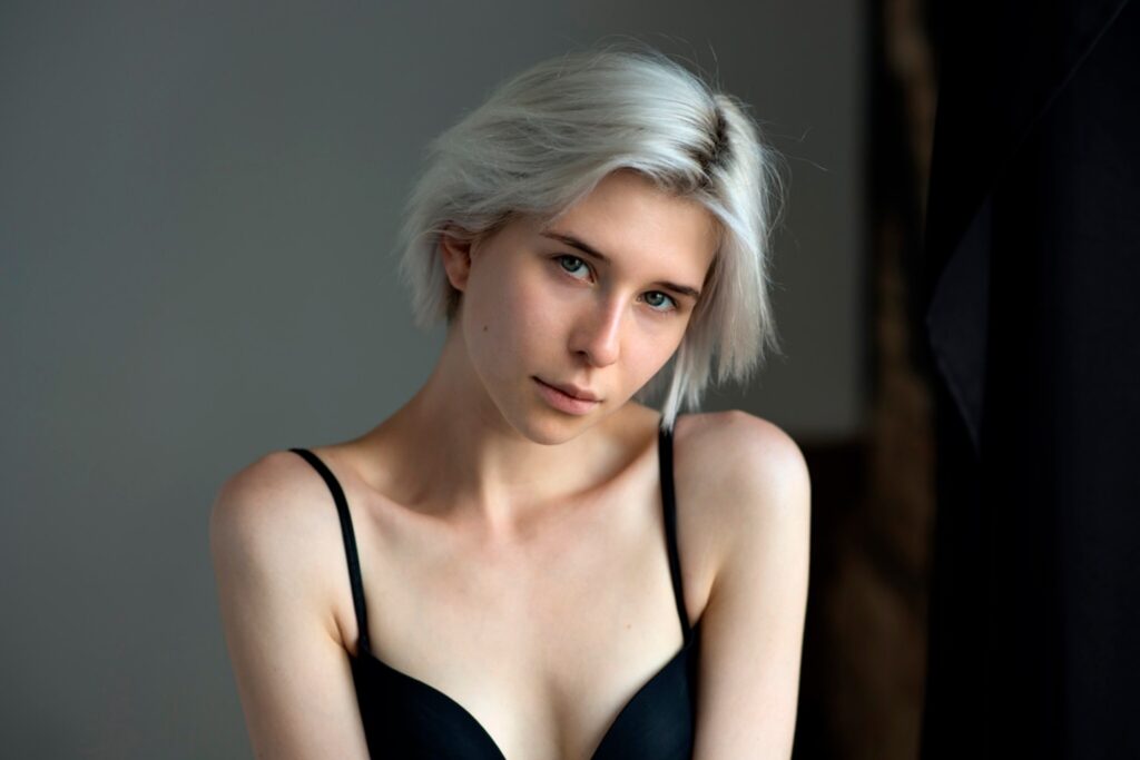 a woman with white hair wearing a black bra
